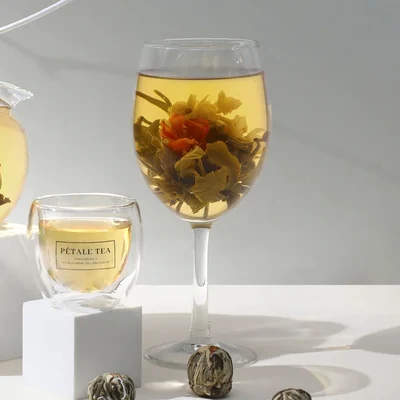 A Celebration tea ball fully opened into a flower in a glass