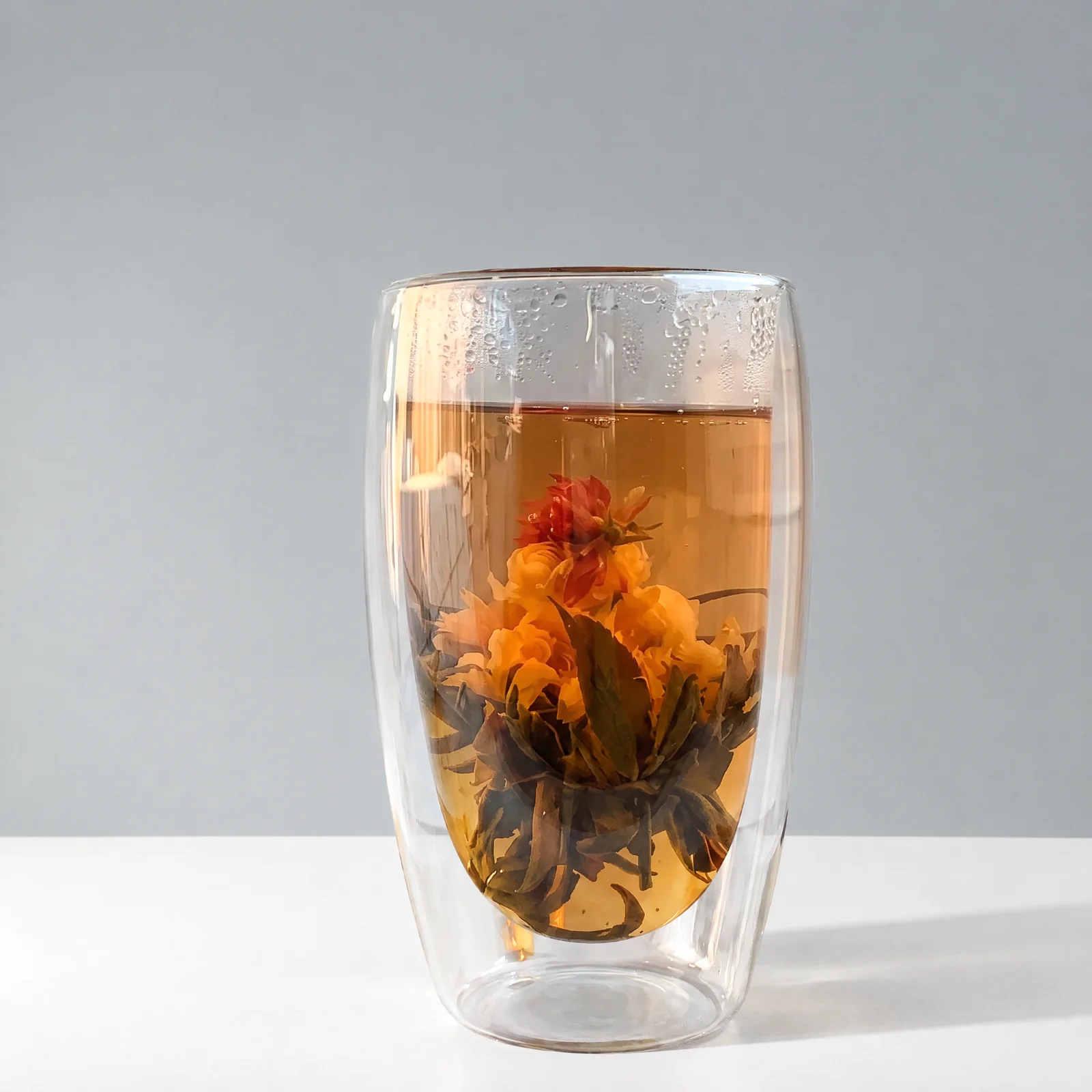 A bloomed tea ball in a clear double-wall glass