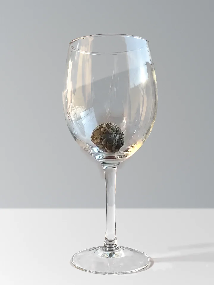 A tea ball in an empty wine glass